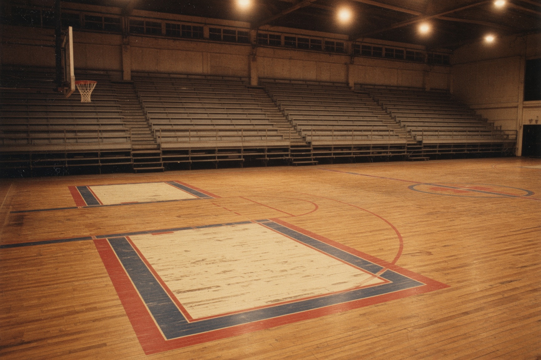 An empty 1970s basketball court with rainbow lane lines and warm overhead lights